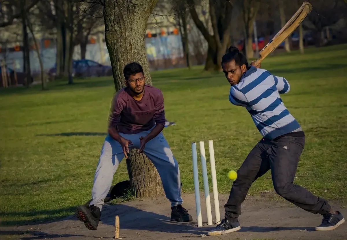 Two men playing cricket in a city park